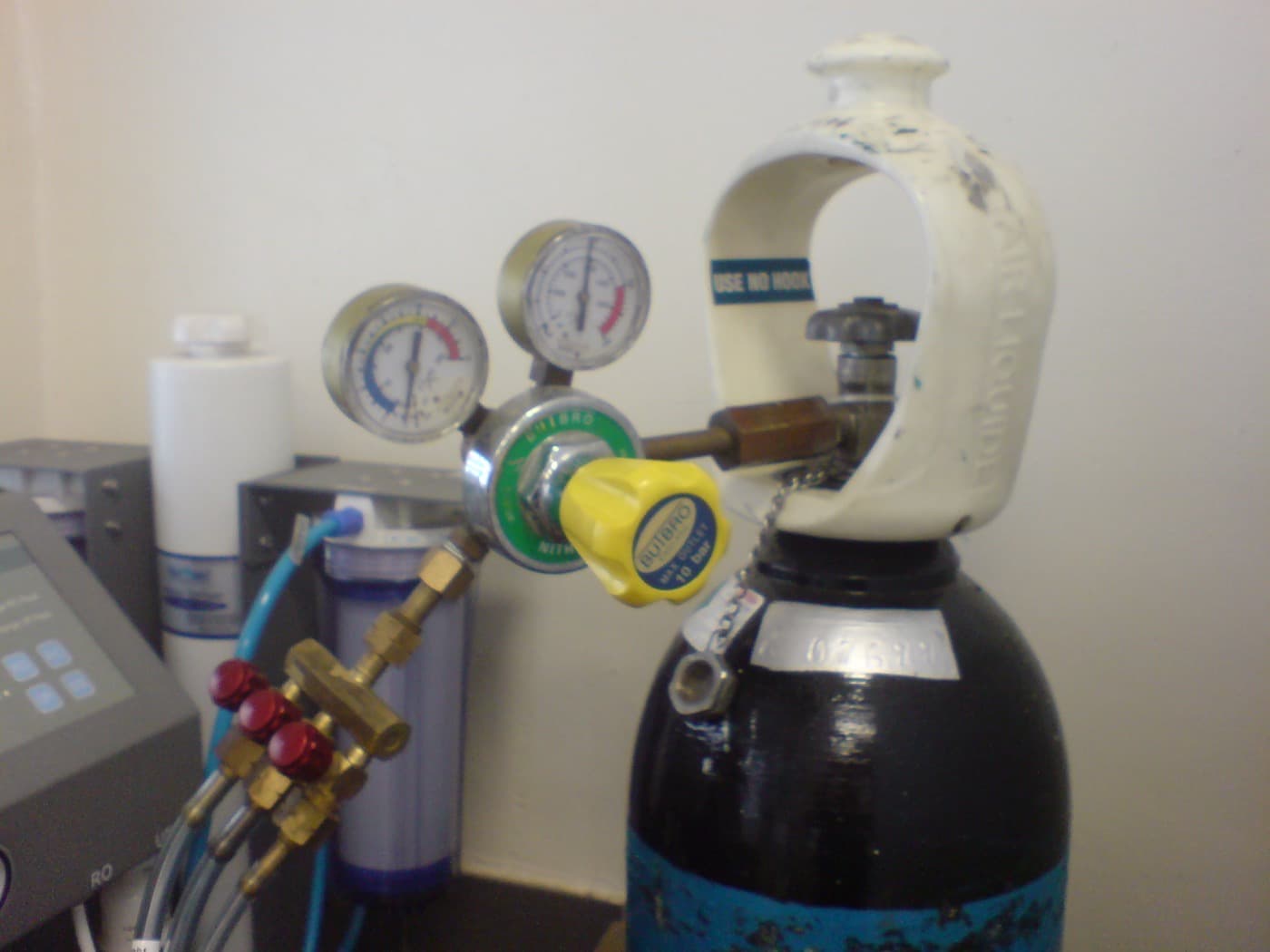 A gas regulator with a three-way outlet and needle valves attached to a cylinder.